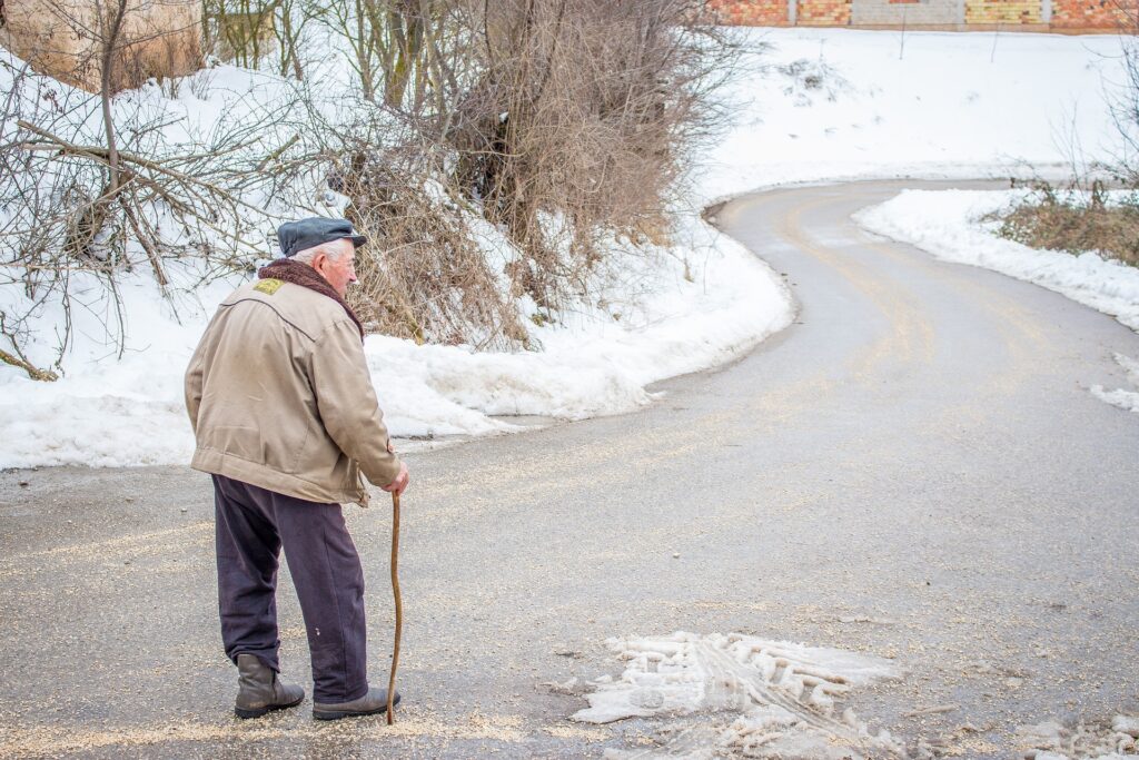 Older man with cane on a snowy road