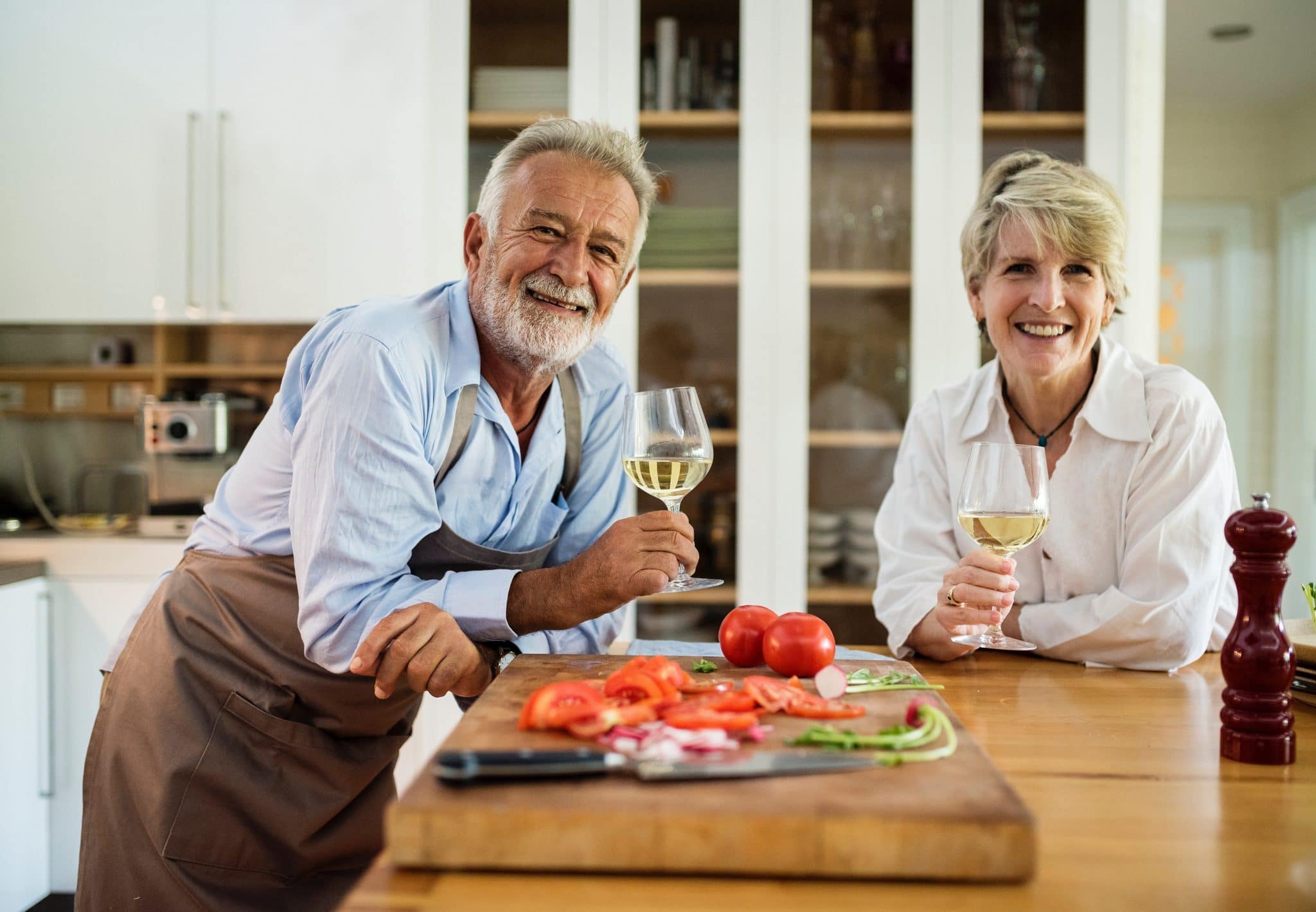 Older couple with wine glasses in hand in a kitchen